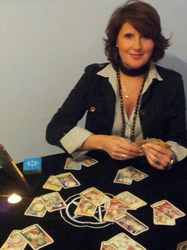 Silvia Sedano ante una tirada de tarot completa, con una vela encendida sobre el tapete